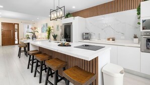 A modern kitchen with a marble backsplash, wooden accents, and bar stools.