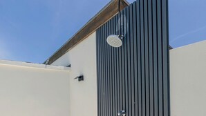 A modern building with a dark vertical panel wall, a small circular window, and a door with a handle.