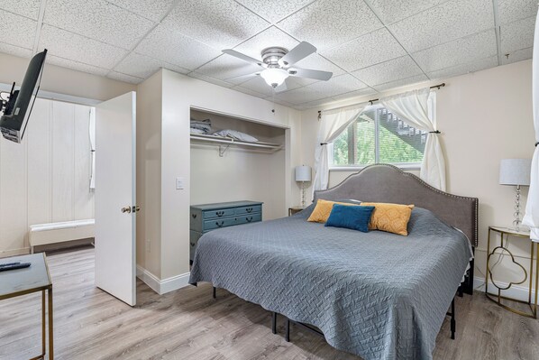A bedroom with a bed, a ceiling fan, a window with curtains, and a dresser. - 4BR Beach House Spacious Steps From Sand (New Smyrna Beach)