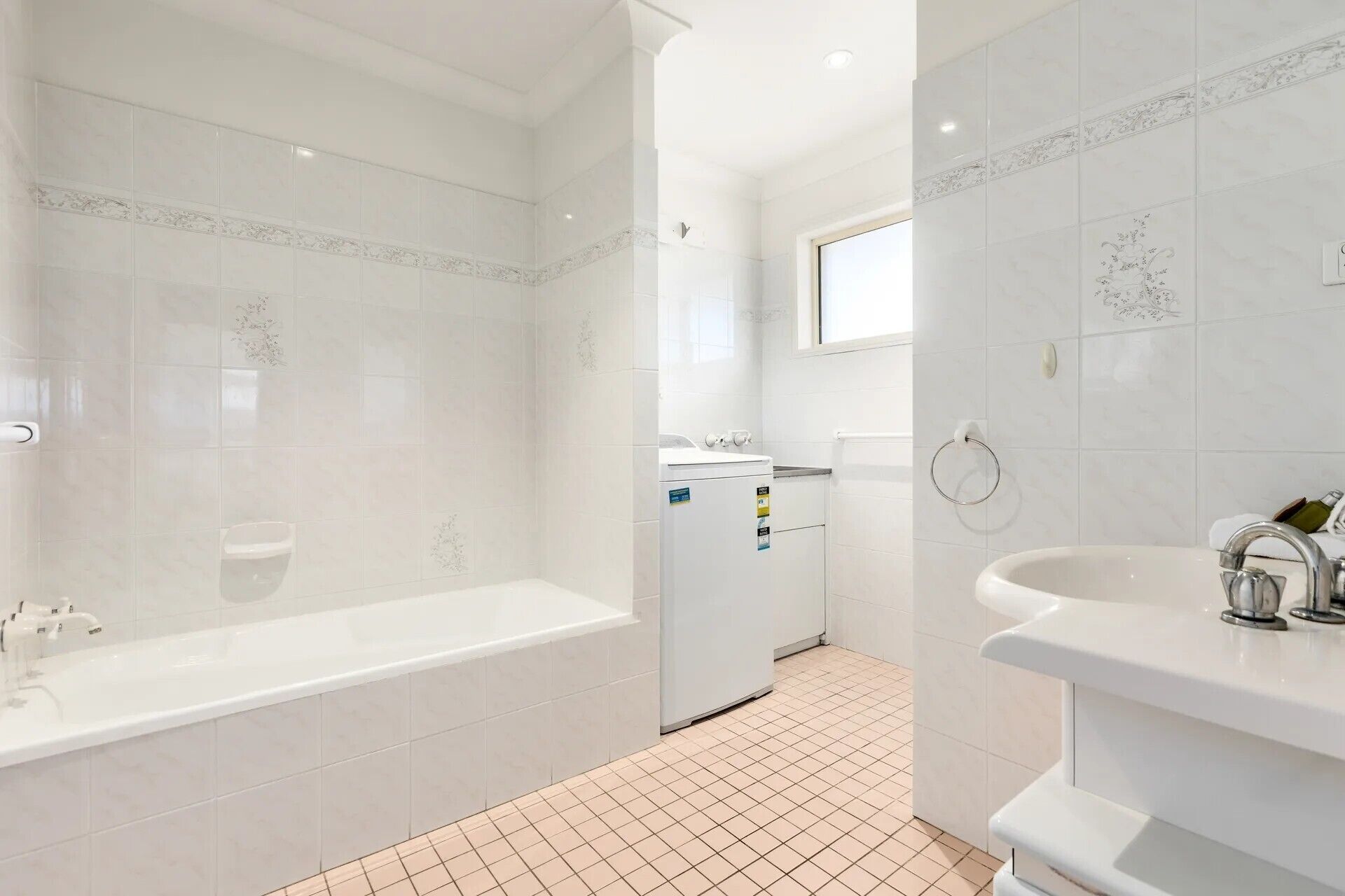 Ein modernes Badezimmer mit Badewanne, Waschbecken und einer kleinen Wäscheecke.