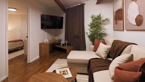 Una sala de estar moderna con un sofá, una mesa de centro, un televisor de pantalla plana, una planta y obras de arte en la pared.