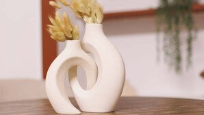 Un jarrón de cerámica blanca con un diseño original sobre una mesa de madera.