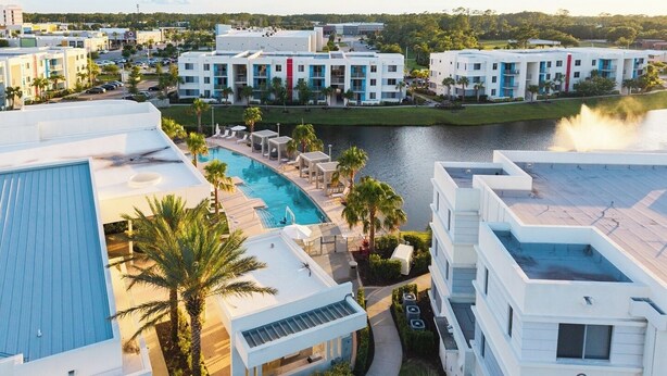 A resort with a swimming pool, multiple buildings, and a body of water. - Spacious 3BR | Pool, Gym, Near Beach and Speedway (Daytona Beach)