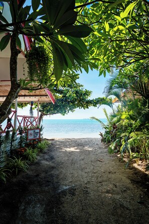 A pathway leading to a beach with a no parking sign, surrounded by lush greenery and a clear view of the sea.