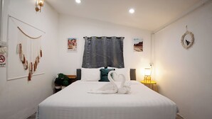 A hotel room with a bed, a wall-mounted light, a curtain, a framed picture, and a wall decoration. - Oceanfront Villa at Bang Po Beach (Koh Samui)