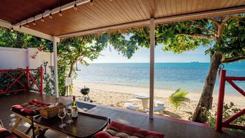 Un espacio de estar al aire libre techado, con vista a la playa y al océano.