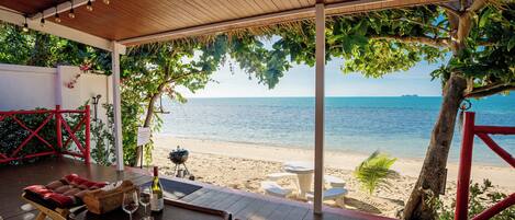 A covered outdoor seating area with a view of the beach and ocean.