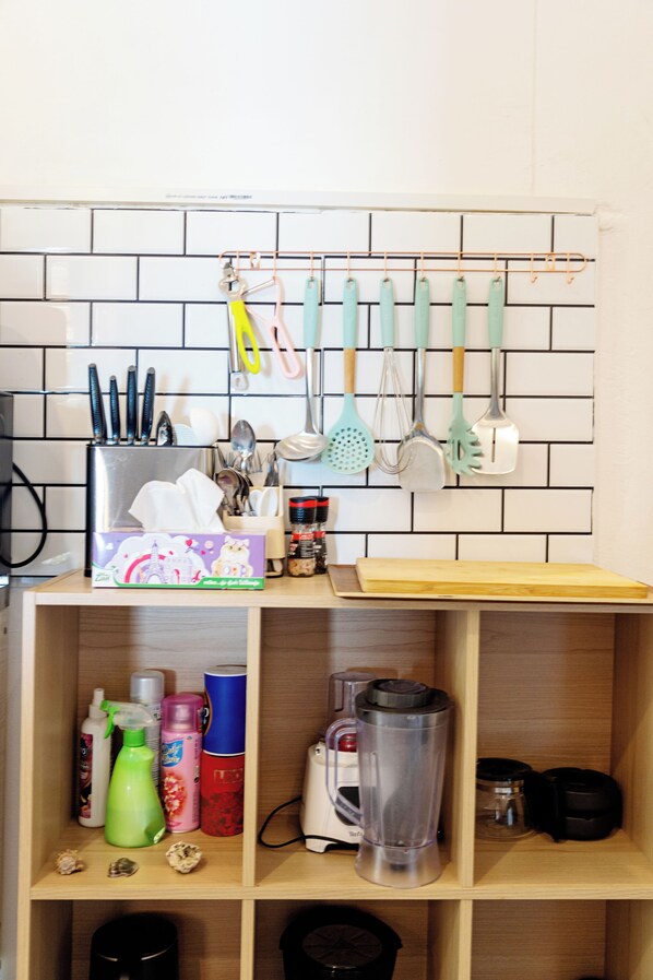 A kitchen with a wooden shelf holding cleaning supplies, a blender, and a box of tissues.