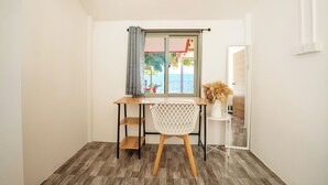 A room with a wooden desk, a white chair, a window with a view of the sea, and a small table with a vase. - Oceanfront Villa at Bang Po Beach (Koh Samui)