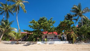 A beachfront property with palm trees, a red-roofed building, and a sandy beach. - Oceanfront Villa at Bang Po Beach (Koh Samui)