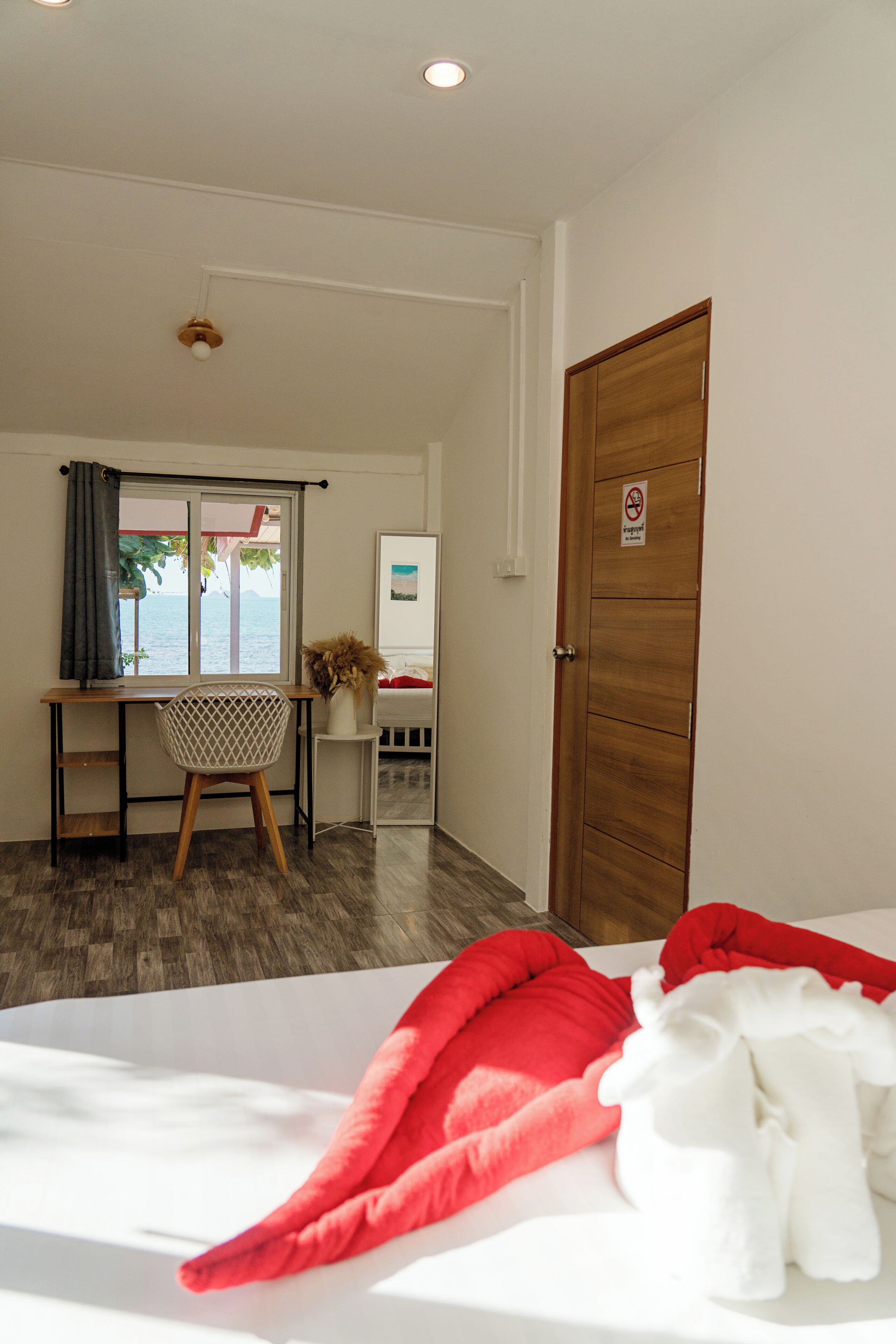 Een kamer met een bed, een bureau met stoel, een raam met uitzicht en een deur met bordje.