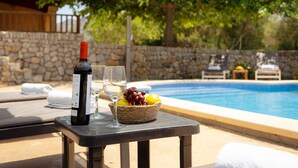 A poolside table with a bottle of wine, a glass, and a basket of fruit. - ES CLAPER - Beautiful estate with private pool and free Wi-Fi in Artà (Artà)