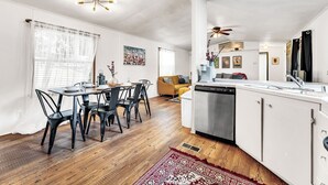 A modern kitchen with white cabinets, a stainless steel dishwasher, and a dining area with a wooden table and black chairs. - Cozy peaceful Lake Palestine Cabin Private dock, Kayak, fire pit Wifi (Chandler)