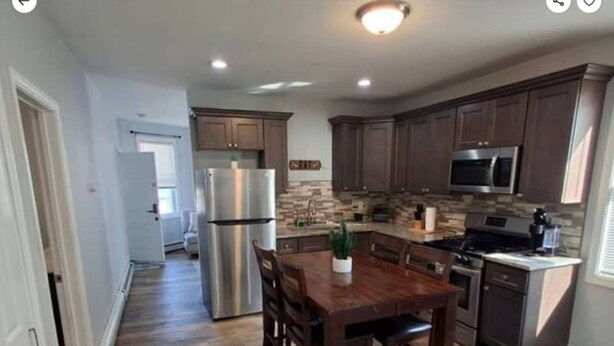 A modern kitchen with dark wooden cabinets, stainless steel appliances, and a central island with seating.