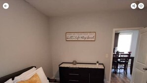 A bedroom with a bed, a dresser, and a wall sign.