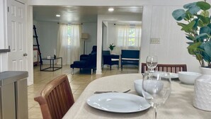 A dining area with a table set for two, a sofa, and a chair in the background. - Getaway by Lakes and Florida Southern, Fully Equipped House Near Top Attractions (Lakeland)