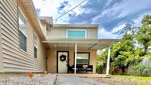 A two-story house with a covered porch, a front door, and a small outdoor seating area. - Getaway by Lakes and Florida Southern, Fully Equipped House Near Top Attractions (Lakeland)