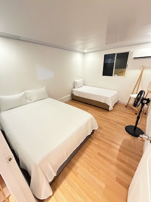A room with a large bed, a smaller bed, a standing fan, and a window with a view. - Lovely house historic with AC in beautiful Cartagena, getsemani (Cartagena)