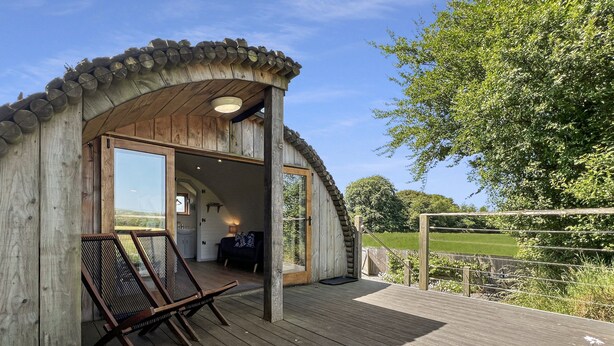 A wooden cabin with a porch, a seating area, and a view of the surrounding landscape. - Exmoor View Log Cabin, nr North Molton (South Molton)