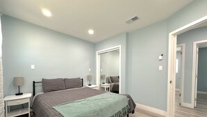 A bedroom with a bed, nightstands, a mirror, and a door leading to another room. - Stay Near Disneyland – Clean, Spacious Anaheim Home for Families & Friends (Anaheim)