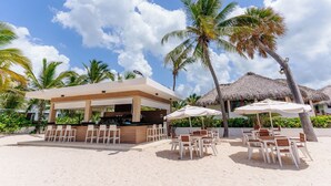 Eine Strandbar mit Außenbestuhlung und strohgedeckten Strukturen.