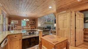 A wooden interior with a kitchen area, stone wall, and a fireplace.