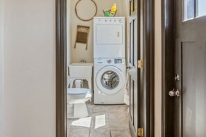 A laundry room with stacked washers and dryers, a toilet, and a small sink. - 1890: A Historic, Quiet Trailside Retreat in Suring (Suring)