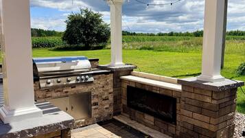 An outdoor kitchen with a grill and a built-in oven, under a pergola with string lights.