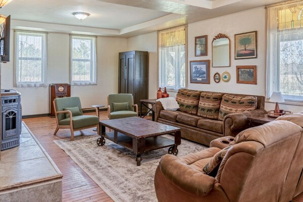 A cozy living room with a fireplace, leather sofa, armchairs, and a coffee table. - 1890: A Historic, Quiet Trailside Retreat in Suring (Suring)