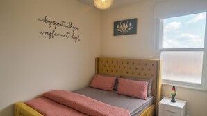 A bedroom with a bed, a bedside table, a nightstand, a window with blinds, and a wall decoration. - 2 Bed - Sleeps 6 - Private Balcony - City Centre (Wolverhampton)