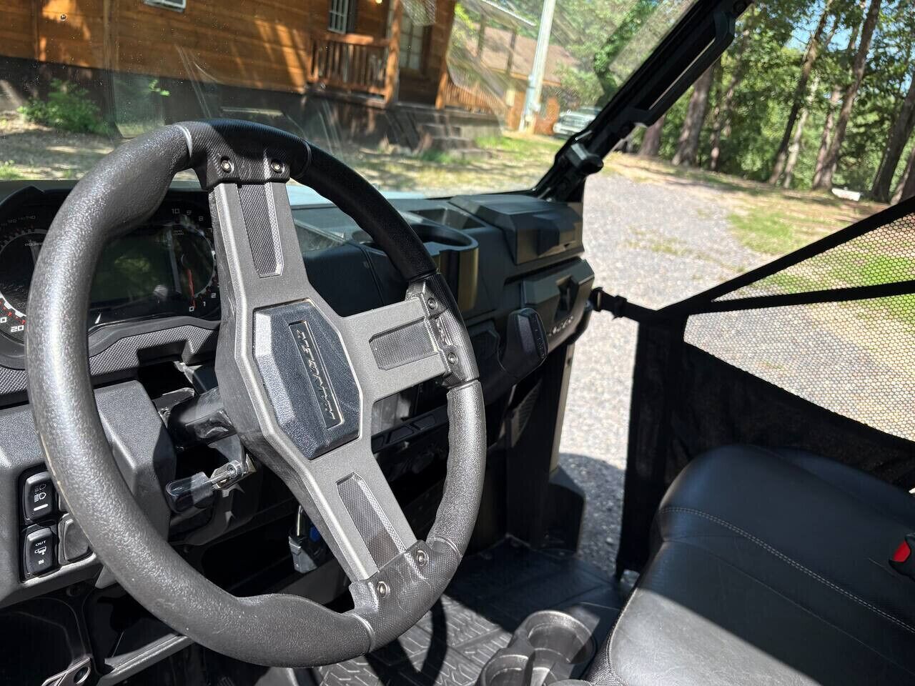 Een voertuiginterieur met stuurwiel, dashboard en stoel.