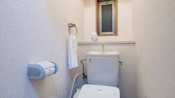A compact bathroom with a toilet, a hand dryer, and a towel rack.