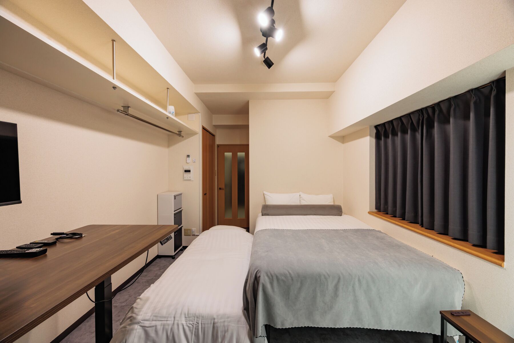 Ein Hotelzimmer mit einem Bett, einem Schreibtisch, einem Fernseher, einem Kleiderschrank und einem Vorhangfenster.