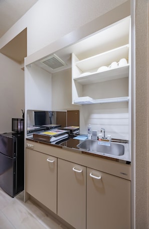 Eine Küchenzeile mit Kühlschrank, Mikrowelle und Spüle mit Armatur.