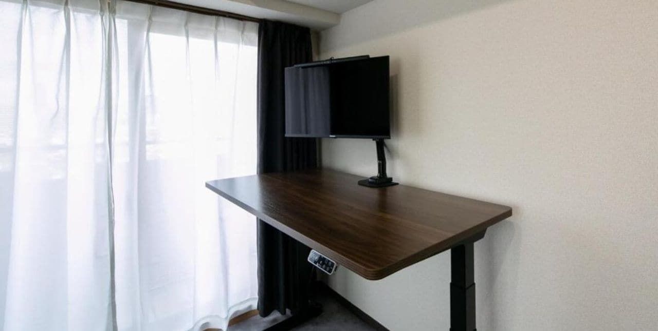 Un escritorio de pie FlexiSpot en una habitación con ventana y cortinas.