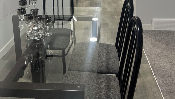 Une cuisine compacte dotée d’appareils électroménagers modernes, un coin repas avec une table et des chaises en verre, et un petit coin salon avec un canapé.