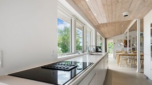 Una cocina moderna con una isla grande, techo de madera y ventanas amplias.