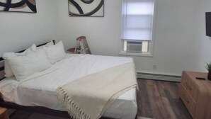 Une chambre à coucher avec un lit, une fenêtre avec des stores, une échelle et une petite table sur laquelle est posée une plante.