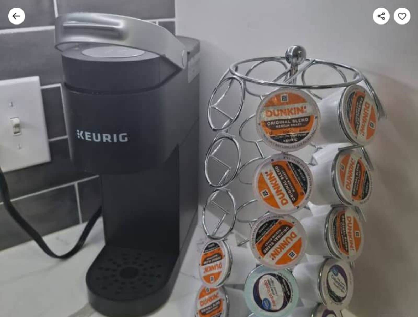 A Keurig coffee maker and a metal dispenser filled with Dunkin' coffee capsules.
