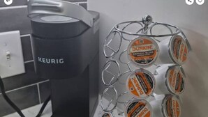 Eine Kaffeemaschine von Keurig und ein Spender aus Metall, gefüllt mit Kaffee-Kapseln von Dunkin'.