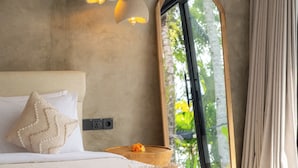 A bedroom with a large bed, a round mirror, and a window with curtains. - Sava Villa Ubud Rice Fields View (Ubud)