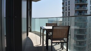 Een balkon met een tafel en stoelen, met uitzicht op een hoog gebouw.