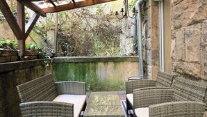 A covered patio area with wicker furniture and a glass table.