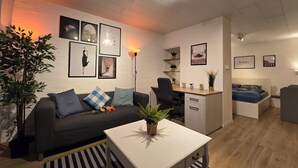 A modern living room with a black sofa, white coffee table, and a desk area.