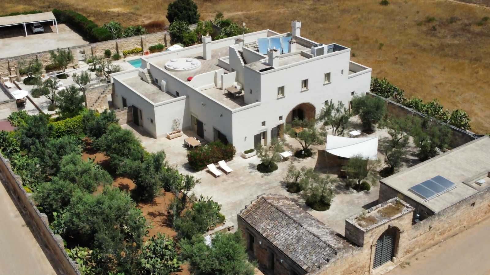 A modern building with a flat roof, solar panels, and a small courtyard with trees and seating areas.
