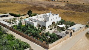 An aerial view of a white building with a central courtyard, surrounded by greenery and a dry landscape. - Cross Vault Suite - Masseria Bernardini (Nardò)