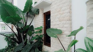 Un edificio de piedra con una ventana pequeña y exuberante vegetación.