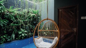 Una silla colgante con un cojín blanco en una habitación con una puerta de madera y un suelo de azulejos azules.