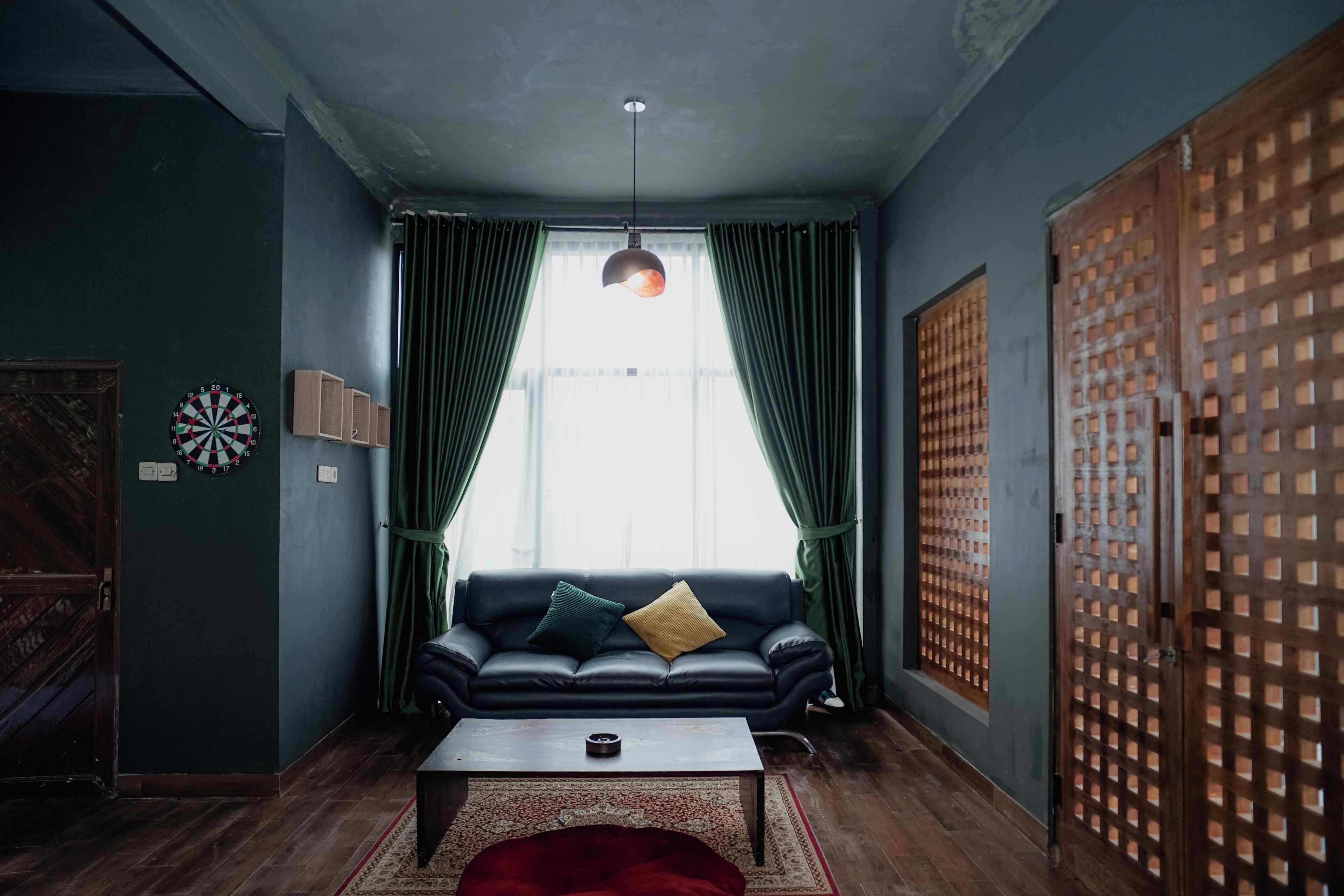 A room with a black leather sofa, a wooden coffee table, and a red throw blanket.