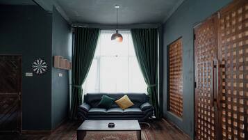 A room with a black leather sofa, a wooden coffee table, and a red throw blanket.